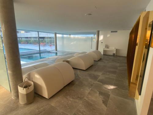 a row of couches in a room with a swimming pool at Hôtel Spa Restaurant Villa Castellane in Gréoux-les-Bains