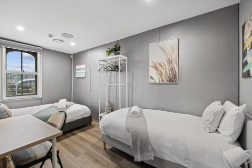 a bedroom with two beds and a table and a desk at Standard Triple Room - Luxe Spot - Next to Central - Shared Bathroom in Sydney