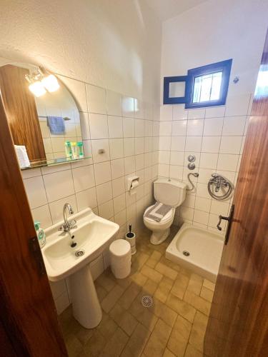 a bathroom with a sink and a toilet and a mirror at Pantelidis Rooms in Skala Potamias