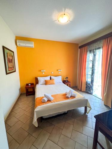 a bedroom with a large bed with orange walls at Pantelidis Rooms in Skala Potamias