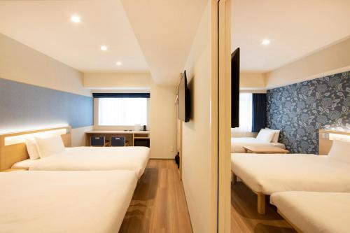 a hotel room with three beds and a window at karaksa hotel TOKYO STATION in Tokyo