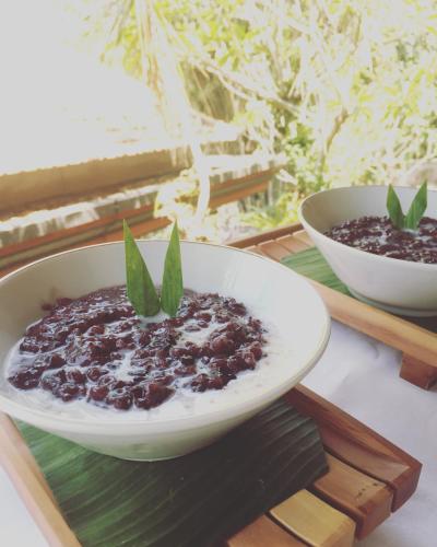 een kom met eten op een houten dienblad met een kom met eten bij Ubud Wins Bungalow in Ubud