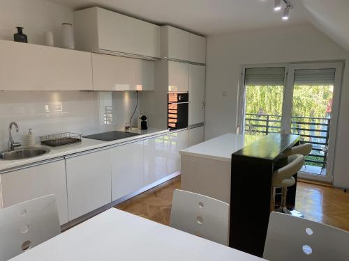 a kitchen with white cabinets and a black counter top at Vila Pobeda in Banja Koviljača