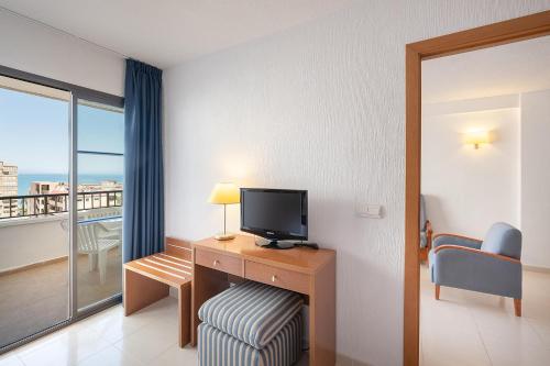 a room with a desk with a television and a balcony at Hotel Playas de Torrevieja in Torrevieja