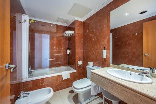 a bathroom with a sink and a tub and a toilet at Hotel Playas de Torrevieja in Torrevieja