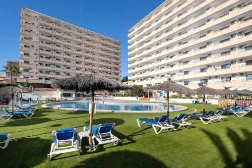 a group of chairs and umbrellas next to a large building at Hotel Playas de Torrevieja in Torrevieja