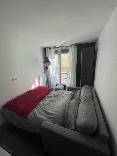 un lit dans une chambre avec un canapé et une fenêtre dans l'établissement Studio lumineux Batignolles, à Paris