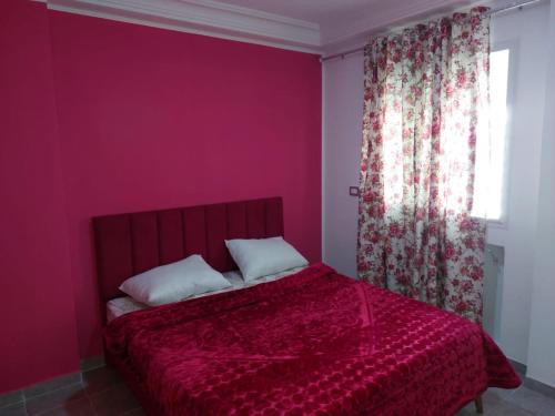 a bedroom with a red bed and a window at Dar Z LeKbira in Tunis