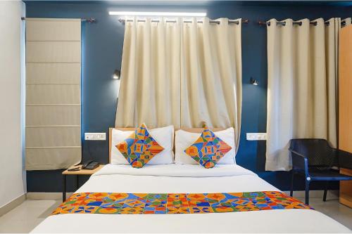 a bedroom with a bed with blue walls and curtains at FabHotel Aura Homes - Nr Khandoba Mandir in Chinchiwad