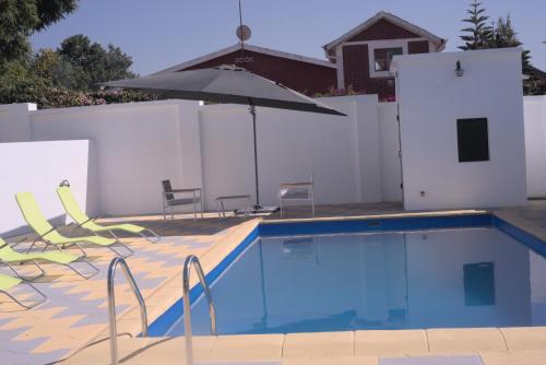a swimming pool with chairs and an umbrella at Résidence La Tonnelle in Antananarivo