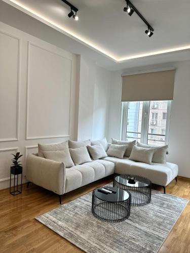 a living room with a white couch and two tables at LU Apartment in Novi Sad