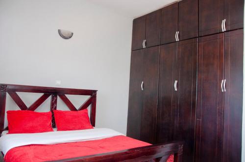 a bedroom with a wooden bed with red pillows at GULOBA Suites in Kampala