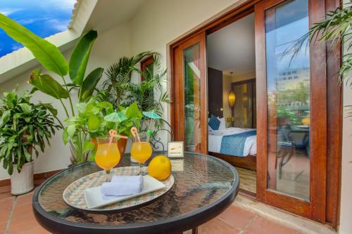 a glass table with a plate of oranges and juice at Oriental Suites Hotel & Spa in Hanoi