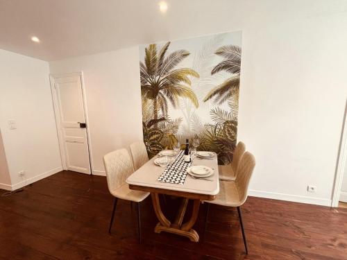 une salle à manger avec une table avec des chaises et une fresque de palmiers dans l'établissement Escalier d'Or ConciergerieDameCarcas, à Carcassonne