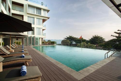 a swimming pool with lounge chairs and a building at Platinum Hotel Jimbaran Beach Bali in Jimbaran