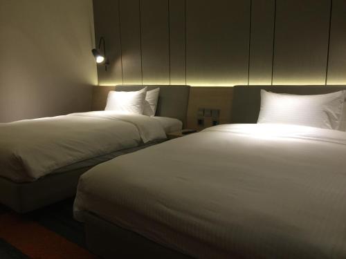 two beds in a hotel room with white sheets at Aerotel Singapore - Transit Hotel in Terminal 1 in Singapore
