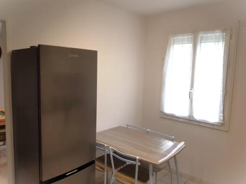 a kitchen with a stainless steel refrigerator and a table at La Barak'A in Saint-Laurent-sur-Mer