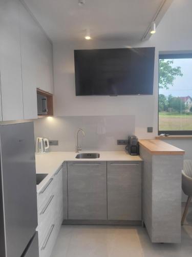 a kitchen with a sink and a tv on the wall at Vilanovka - domki z balią in Wilanowo