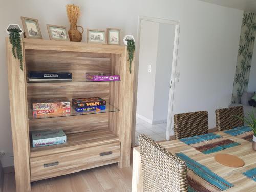 a room with a table and a wooden book shelf at La Barak'A in Saint-Laurent-sur-Mer