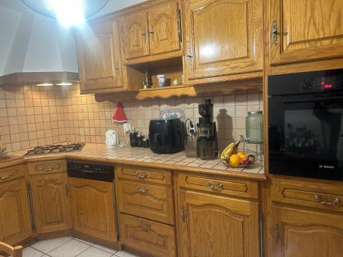 une cuisine avec des armoires en bois et un micro-ondes noir dans l'établissement Maison de rêve proche de stade de France, location pour les jeux olympiques 2024, à Bobigny