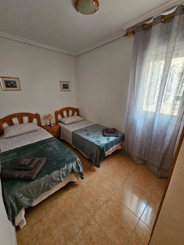 a bedroom with two beds and a window at Casa Aleks Lo Pagan in San Pedro del Pinatar