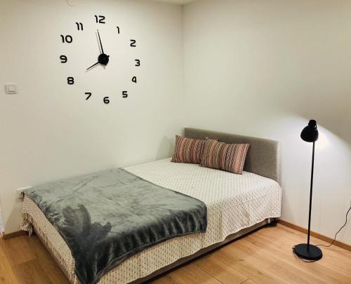 a bedroom with a bed and a clock on the wall at Studio apartman - herlla in Velika Gorica