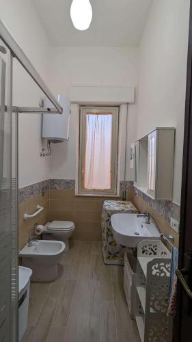 a bathroom with two sinks and a toilet and a window at Vititta Appartamenti in Trapani