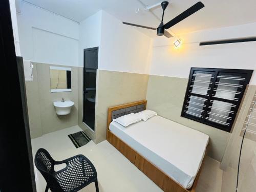 a small bedroom with a bed and a chair at Priya lodge in Kozhikode