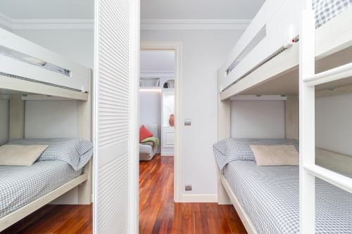 two beds in a room with white walls at El Balcón de Charles in Santander