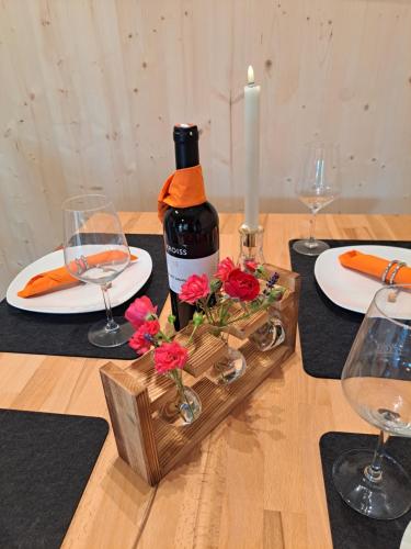 a bottle of wine and flowers on a table with glasses at Ferienhaus und Ferienappartements Brunner in Höchst
