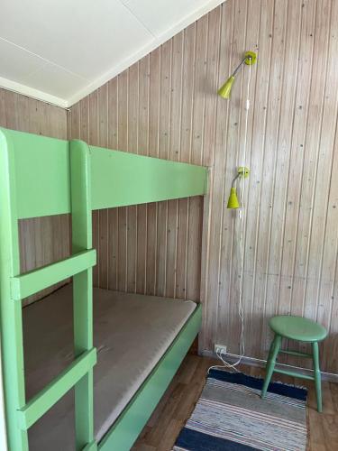 a green bunk bed with a chair and a lamp at Svindland Camping in Kvinesdal
