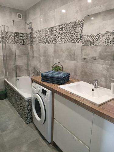 a bathroom with a sink and a washing machine at Sea&Wine Apartamenty Darłówko in Darlowko