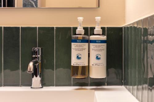 two bottles of soap sitting on a bathroom sink at Numa Rome Barberini in Rome