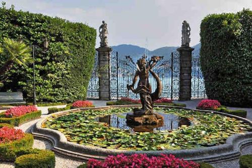 a statue in the middle of a fountain with flowers at Casa Ambra, 50m vom Comer See, 2 private Parkplätze in Tremezzo