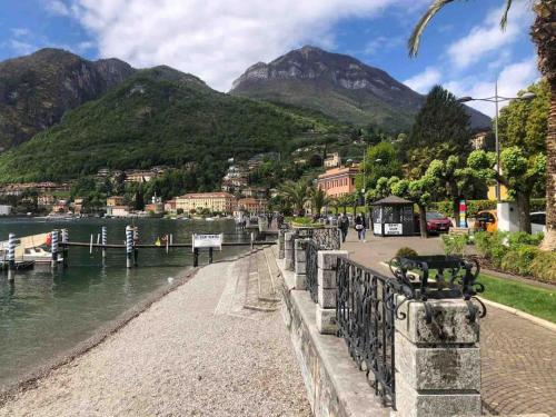 a walkway next to a body of water with mountains at Casa Ambra, 50m vom Comer See, 2 private Parkplätze in Tremezzo
