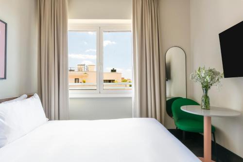 a hotel room with a bed and a table and a window at Numa Rome Barberini in Rome