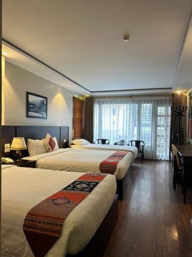 a hotel room with two beds and a desk at Sapa Centre Hotel in Sa Pa