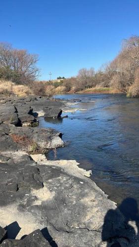a river with some rocks and water and trees at The Loop Farmhouse Mooi River in Mooirivier