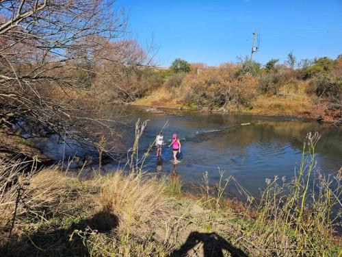 two people standing in the water in a river at The Loop Farmhouse Mooi River in Mooirivier