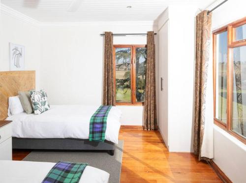 a bedroom with a bed and a window at The Loop Farmhouse Mooi River in Mooirivier