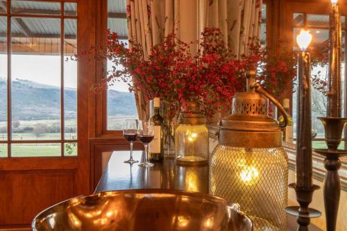 a table with glasses of wine and flowers on it at The Loop Farmhouse Mooi River in Mooirivier