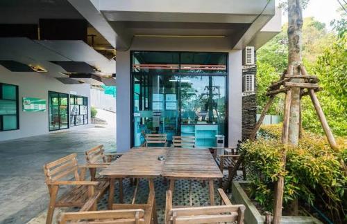 a wooden table and chairs in front of a house at Nice apartment with Pool in Patong Phuket direct on the beach in Kamala Beach