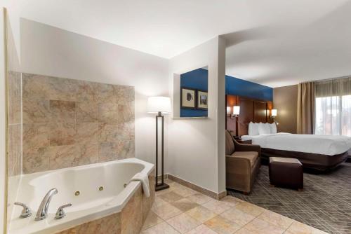a hotel room with a tub and a bed at Comfort Suites Atlanta Airport in Forest Park