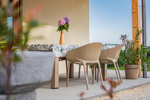 a table with three chairs and a vase with purple flowers at Wellness Počitniška hiša Manja in Ljutomer