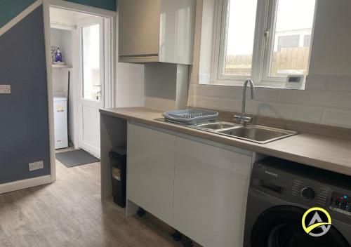 a kitchen with a sink and a washing machine at Delightful London Chalet House in Bromley