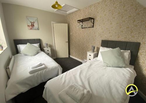 a bedroom with two beds with white sheets at Delightful London Chalet House in Bromley