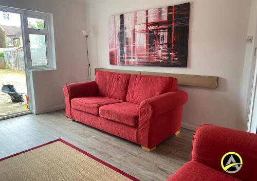 a red couch sitting in a living room at Delightful London Chalet House in Bromley