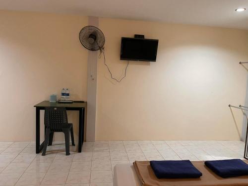 Habitación con mesa y TV en la pared. en โรงแรมเมโทร2 Metro2, en Satun