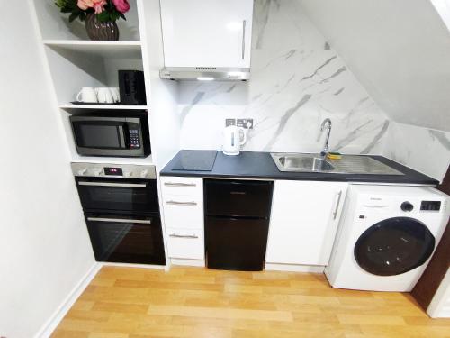 a small kitchen with a sink and a microwave at The Swans - Two-Bedroom City Centre House with Parking in Oxford