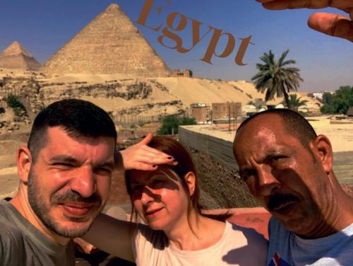 two men and a woman standing in front of the pyramids at Energy Of Pyramid Hotel in Cairo